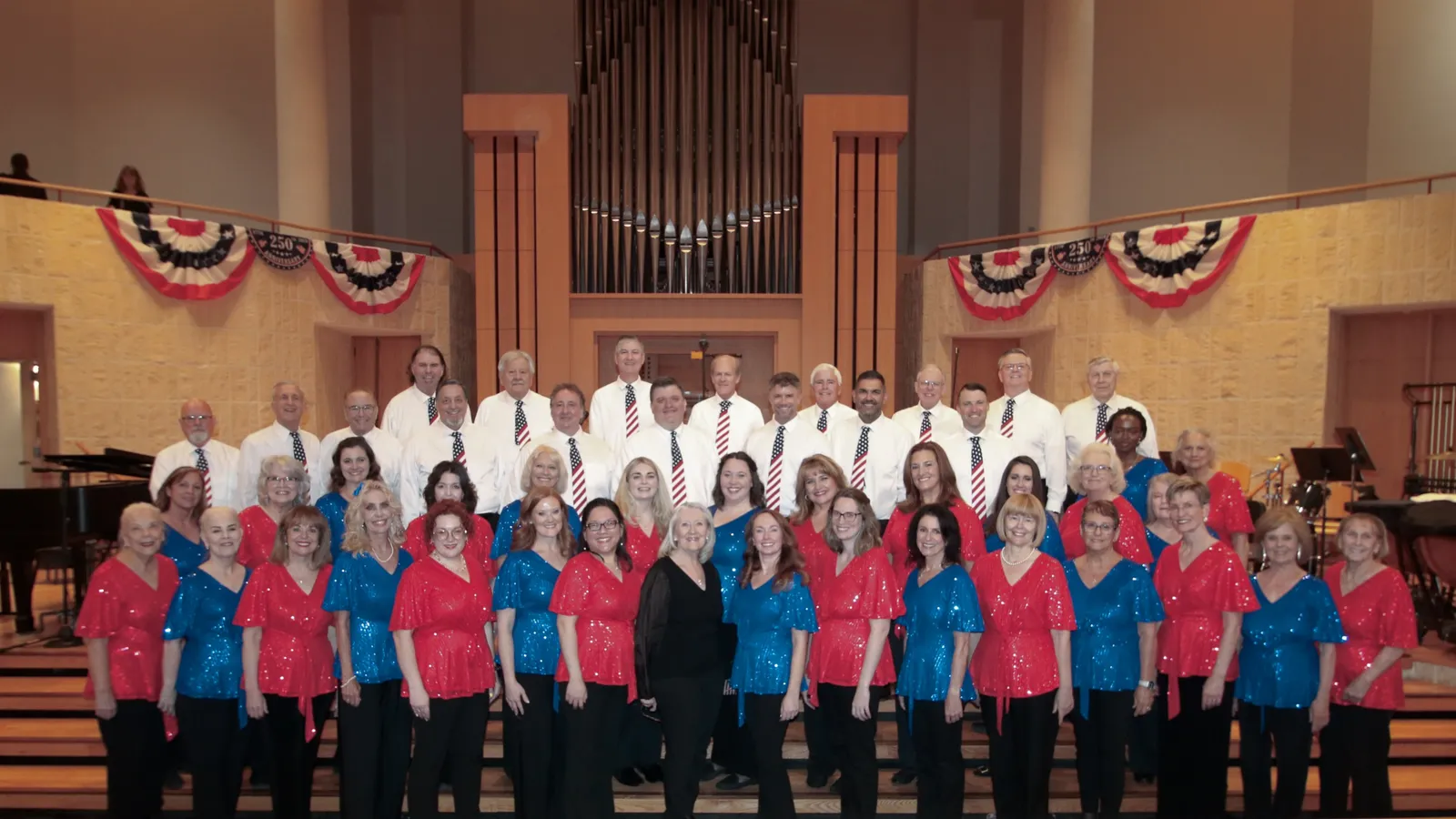The full North Valley Chorale on risers, patriotic bunting behind them